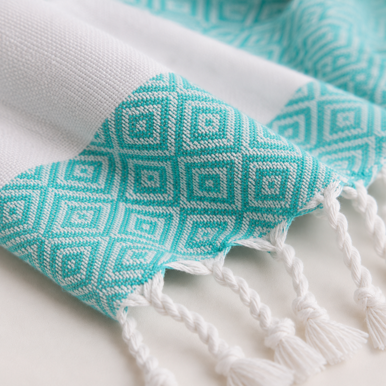Close-up of turquoise geometric weave and knotted tassels